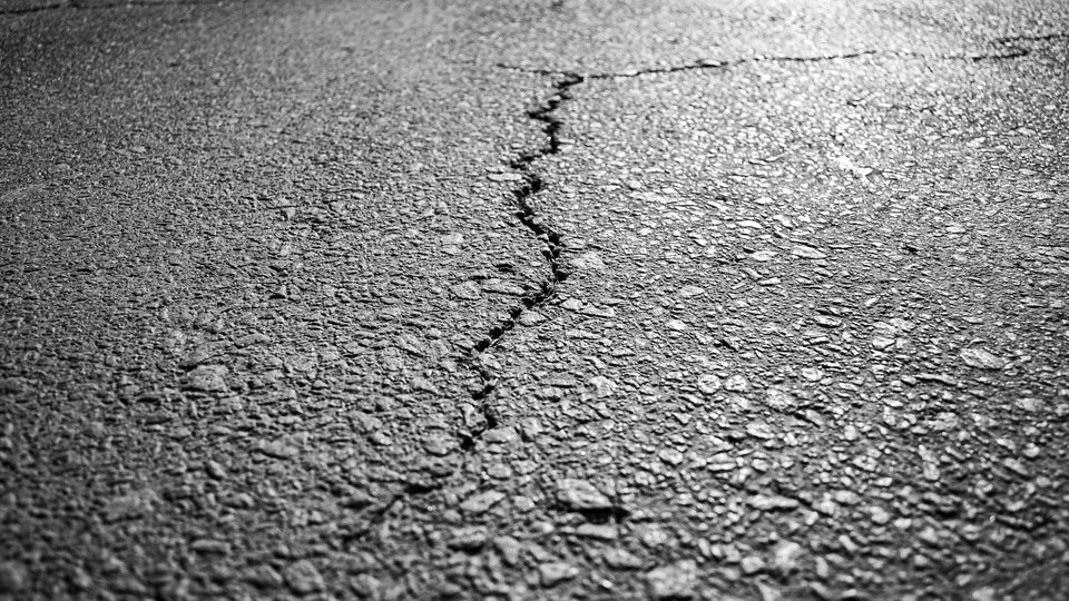 Close-up of a crack running through an aged asphalt surface